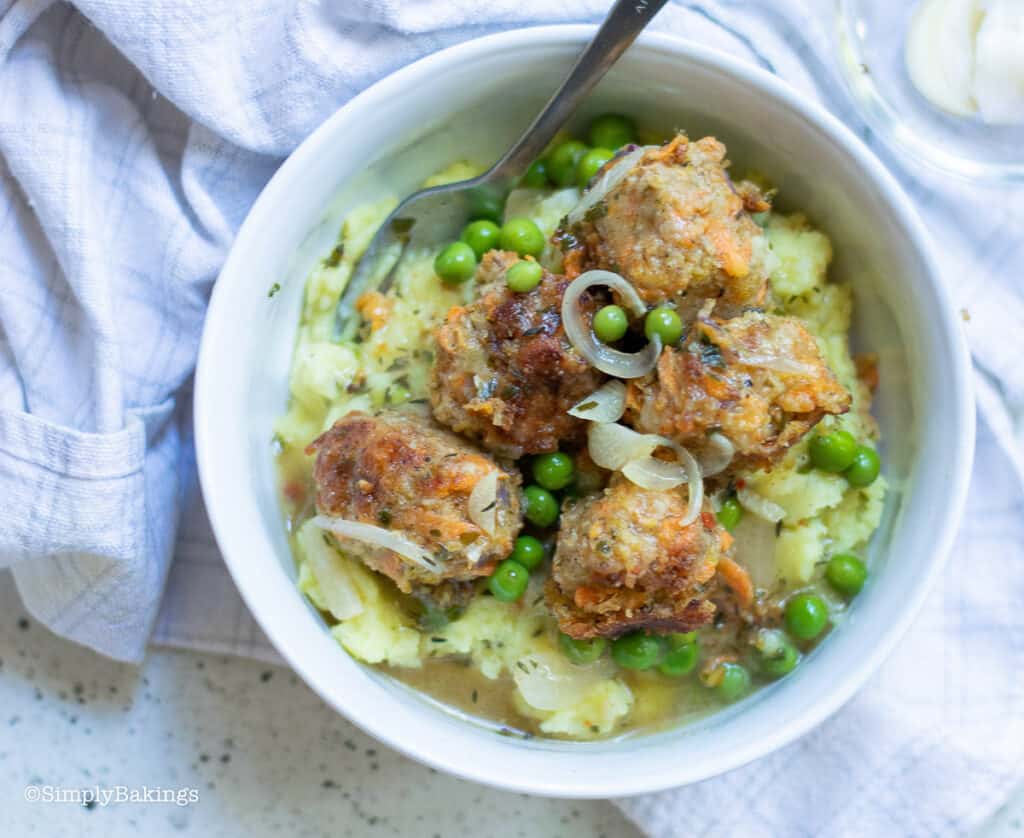 a bowl of healthy and delicious vegan meatballs with mashed potatoes and vegetarian gravy