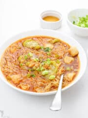 a savory vegan misua soup in a white bowl with a stainless spoon