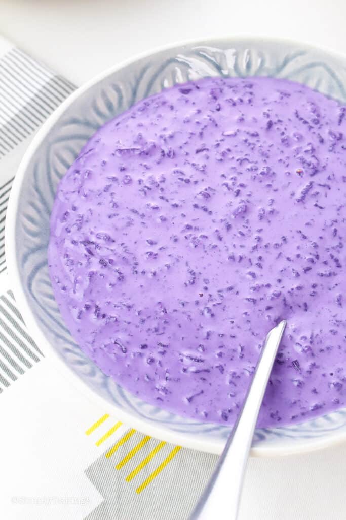 ube champorado in a bowl with a stainless spoon
