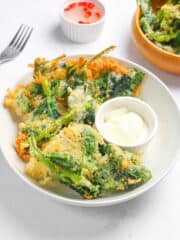 crispy kangkong and a dipping sauce served on a white plate