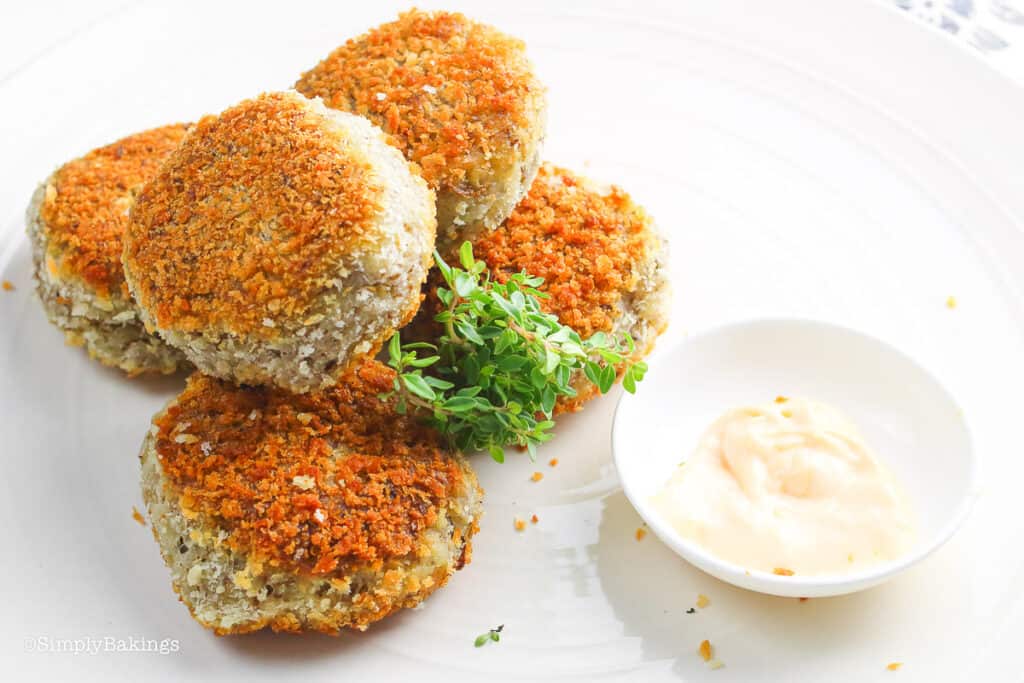 vegan fishless cakes on a white plate with a dipping sauce small bowl