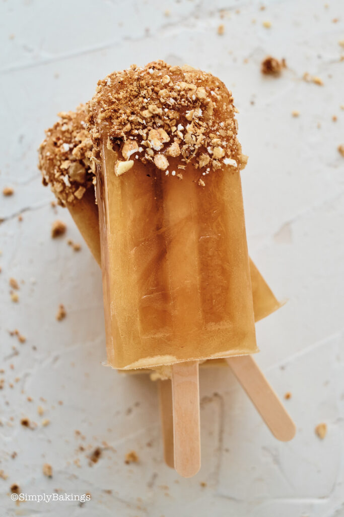 delicious apple cider popsicles dipped with caramel sauce and crushed granola