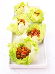 delicious tofu adobo lettuce wraps on a white rectangular serving plate