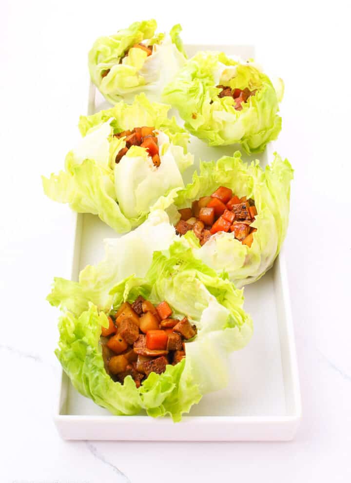 delicious tofu adobo lettuce wraps on a white rectangular serving plate