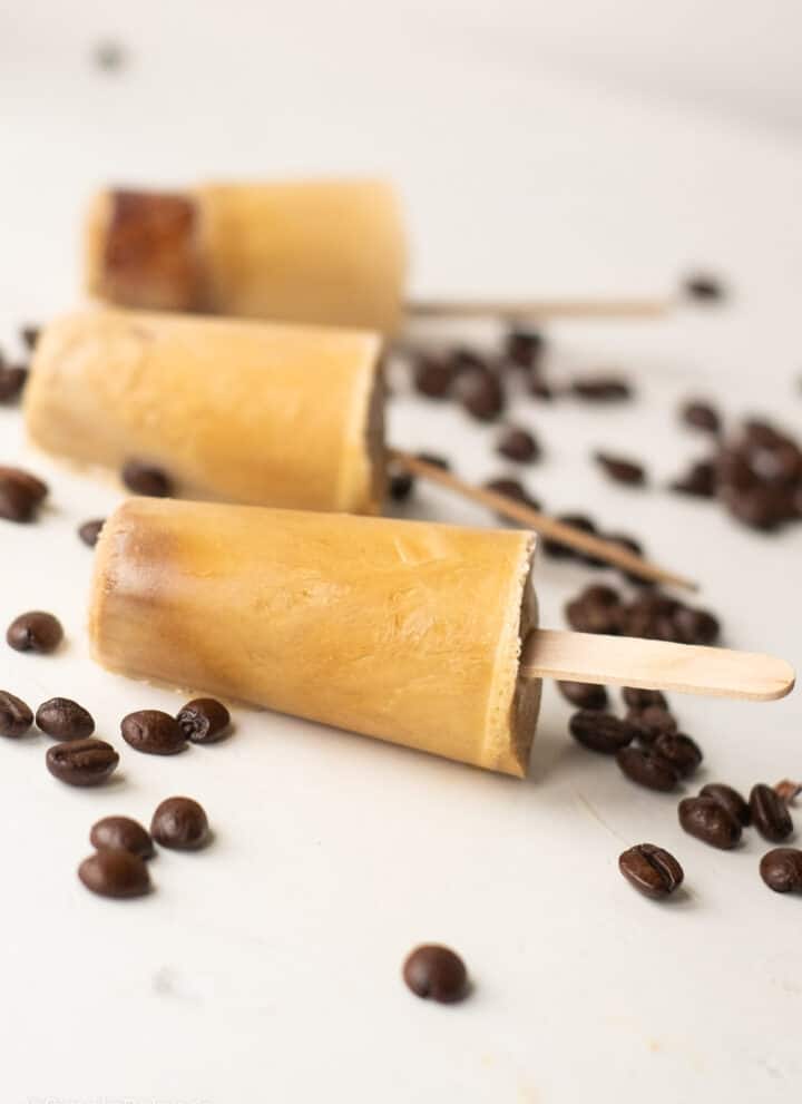 delicious Vietnamese Iced Coffee Popsicles on a white surface with coffee beans