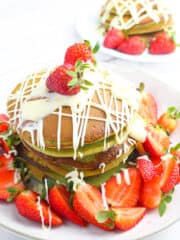 matcha souffle pancakes served on a white plate and garnished with strawberry slices