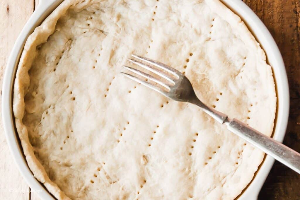 pie crust on a pie plate with a stainless fork