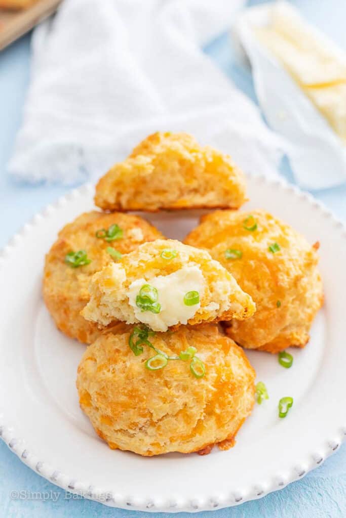 breakfast biscuits on a white plate halved with butter and scallions