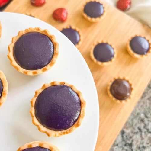 Ube tarts on a white plate and board
