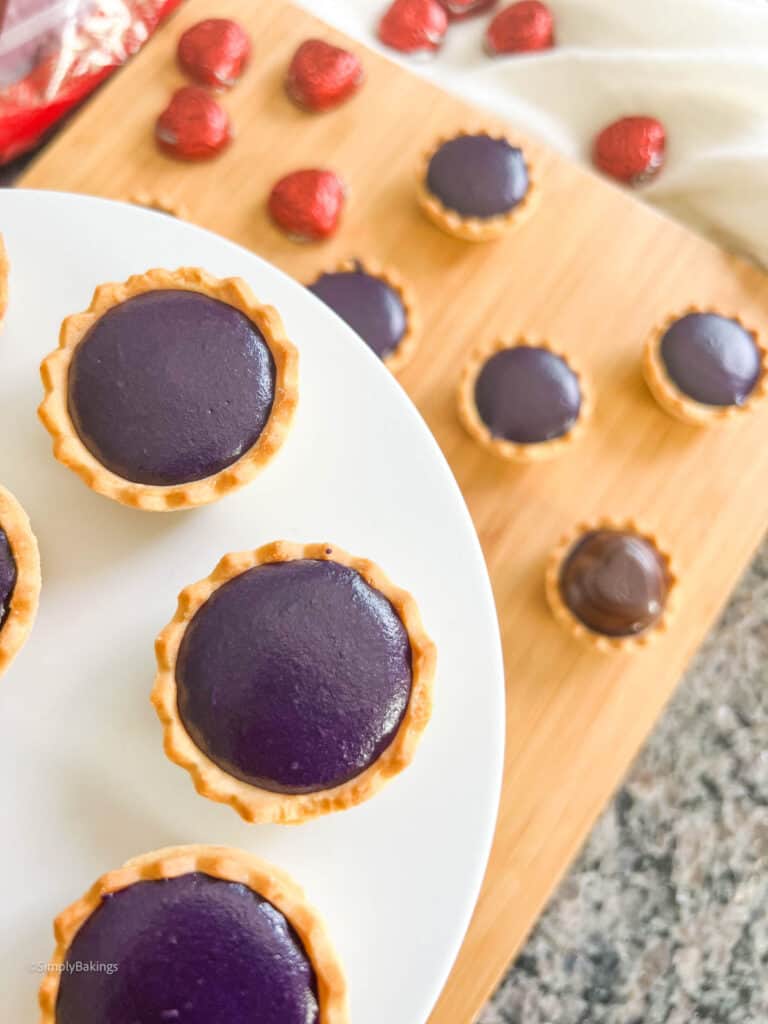 some ube tarts on a white plate and some on the wooden board