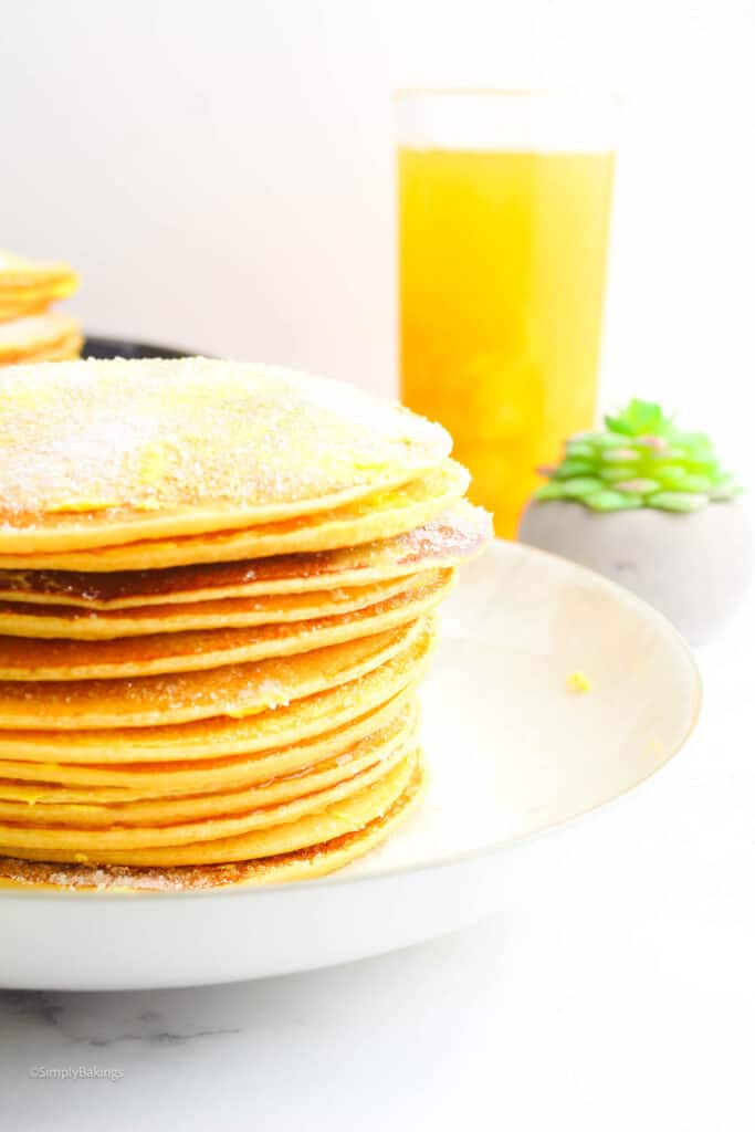 pinoy pancakes stacked on a plate with a glass of orange juice