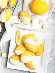 Lemon madeleine cakes covered with white chocolate set on a white plate