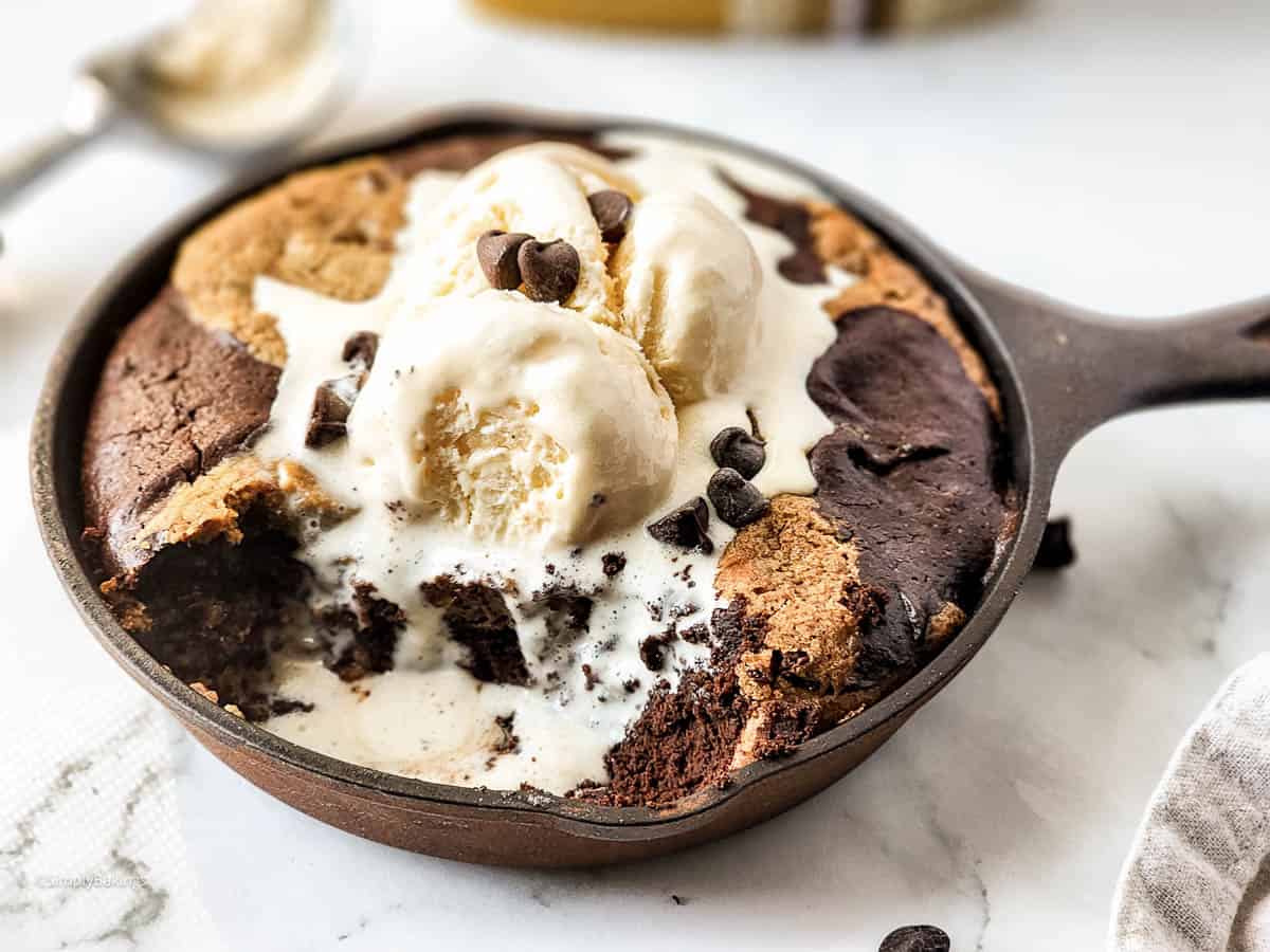 sweet and delicious skillet brookie topped with vanilla ice cream and chocolate chips