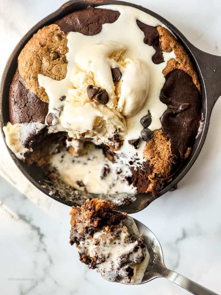 a spoonful of skillet brookie with vanilla ice cream and chocolate chips toppins