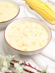 delicious Filipino ginataang mais served in bowls beside a fresh sweet corn and a few white flowers