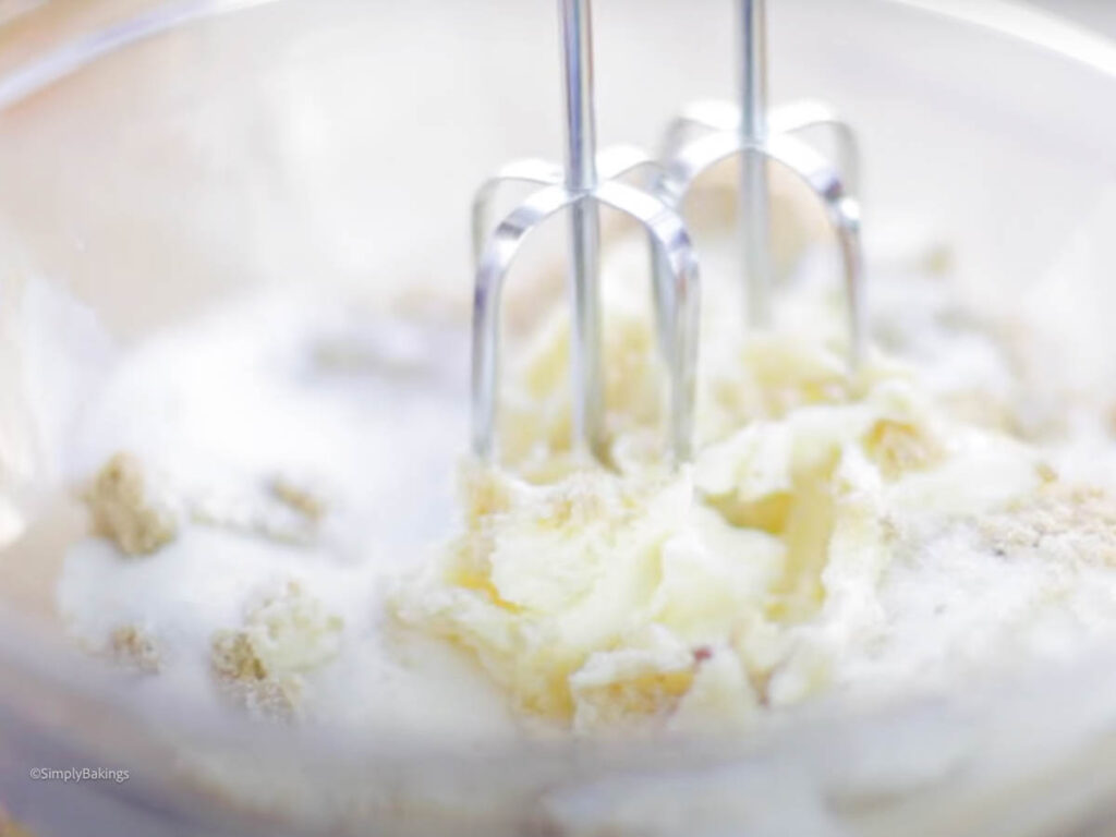 sugar and butter mixed with beaters in a glass bowl