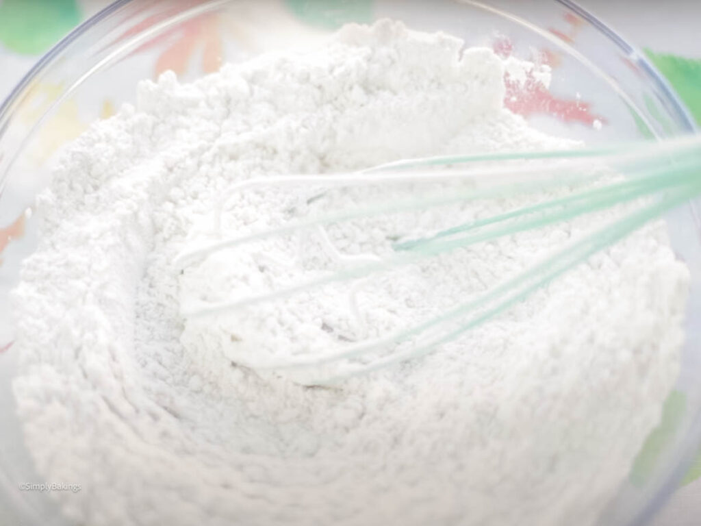 a glass bowl with flour with a whisk