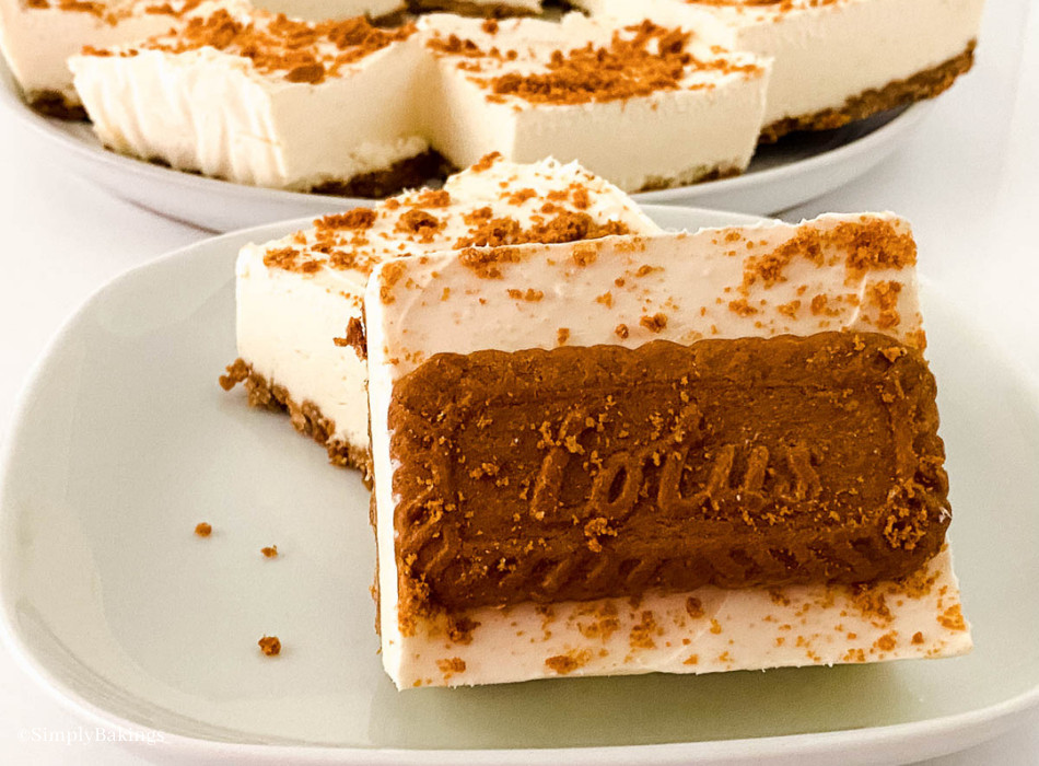 slices of biscoff cheesecake bars topped with lotus cookie on a grayish plate