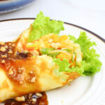 lumpiang sariwa with peanut sauce on a round white plate