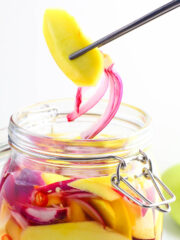 a jar of pickled mangoes with red chilies and red onion slices