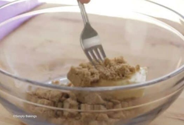 Mixing brown sugar and butter with a fork in a glass bowl
