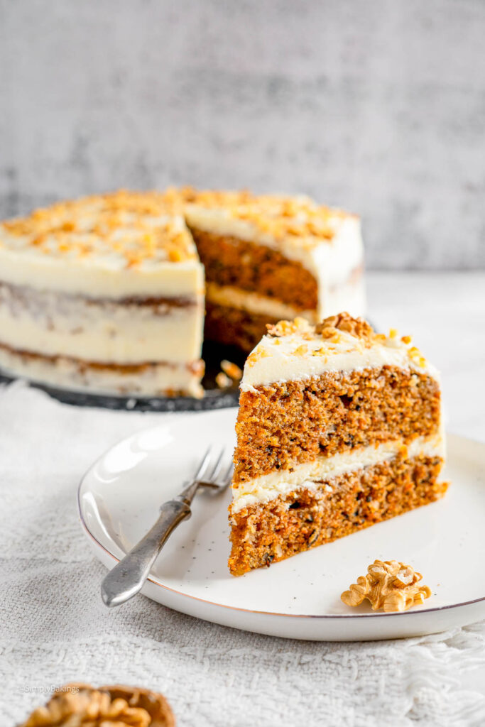 Moist carrot cake garnished with frosting and nuts