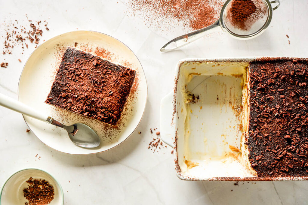 Scooping a slice of tiramisu from the container