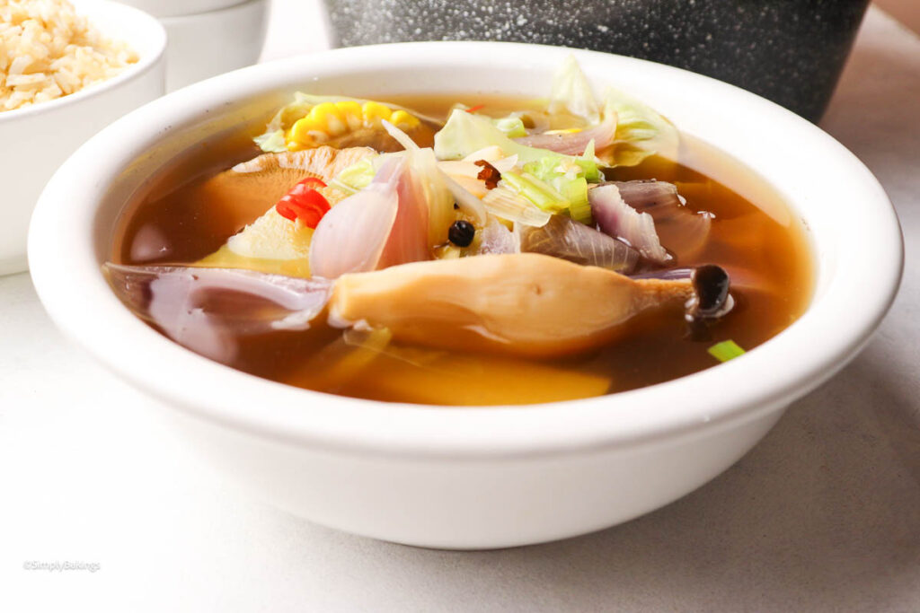 A steaming bowl of veggie soup beside rice