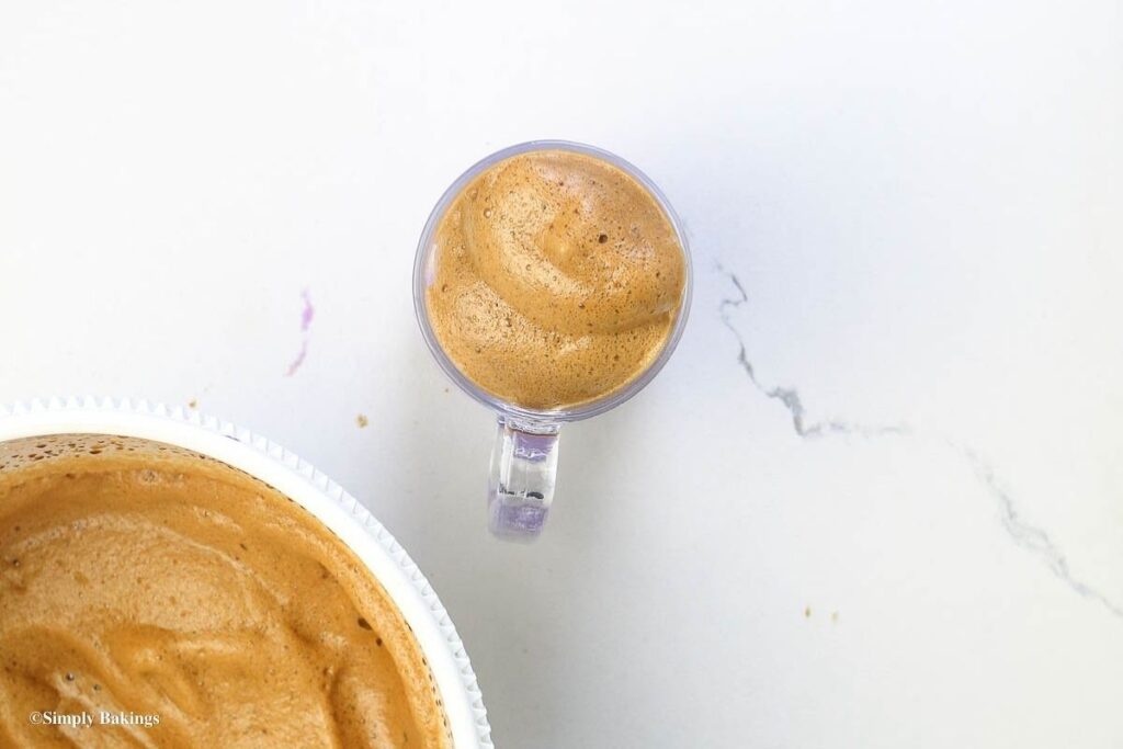 Thick whipped coffee foam on top of glass mug