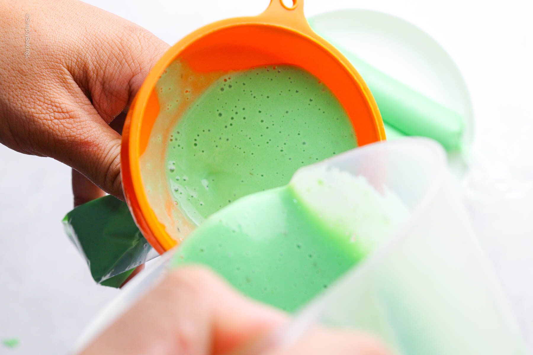 pouring green liquid through funnel