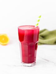 a tall glass of red juice with a green straw