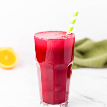 a tall glass of red juice with a green straw