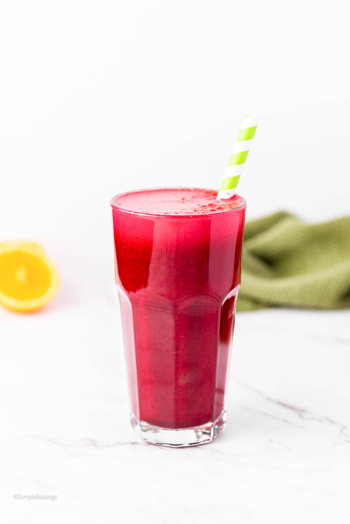 a tall glass of red juice with a green straw