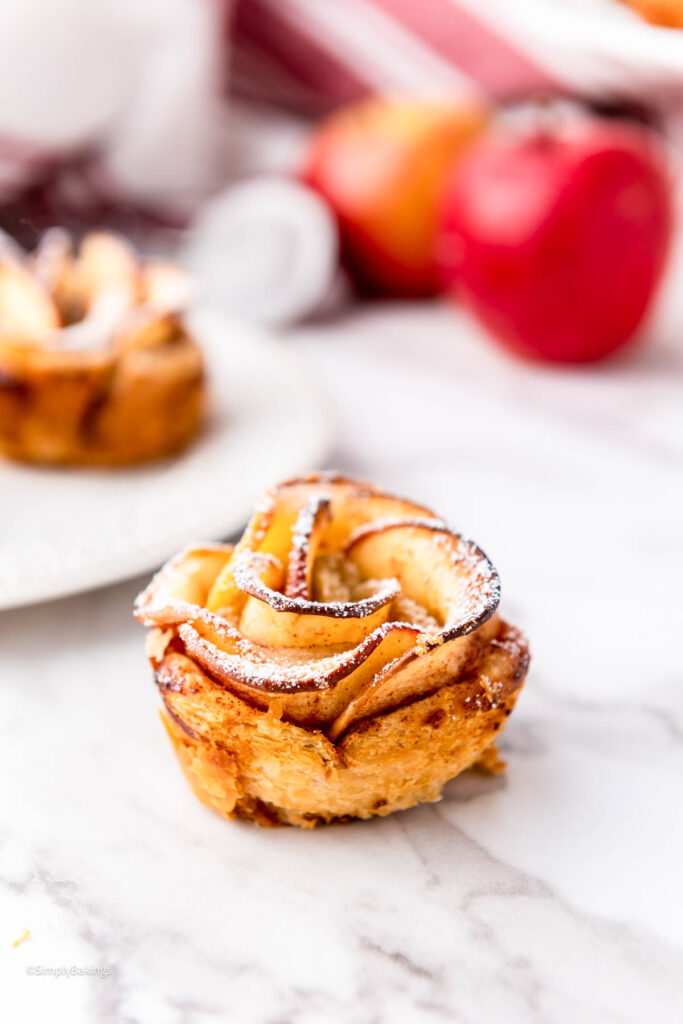 A single Apple Rose on the table next to a plate