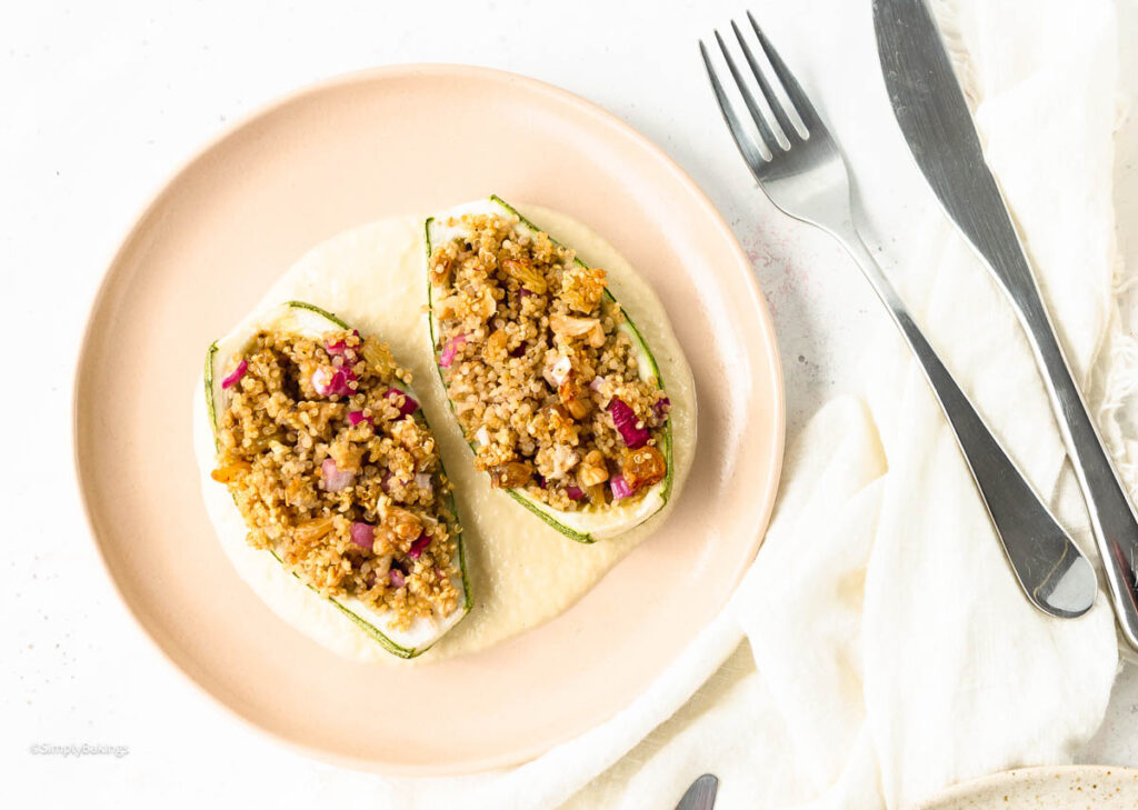 Vegan Stuffed Zucchini on a plate with sauce beside a knife and fork
