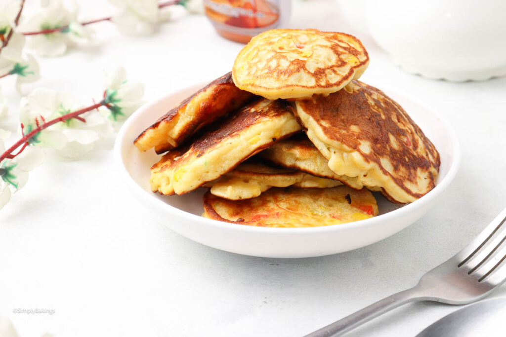 stack of corn Fritters with pancake mix in a white plate beside a fork