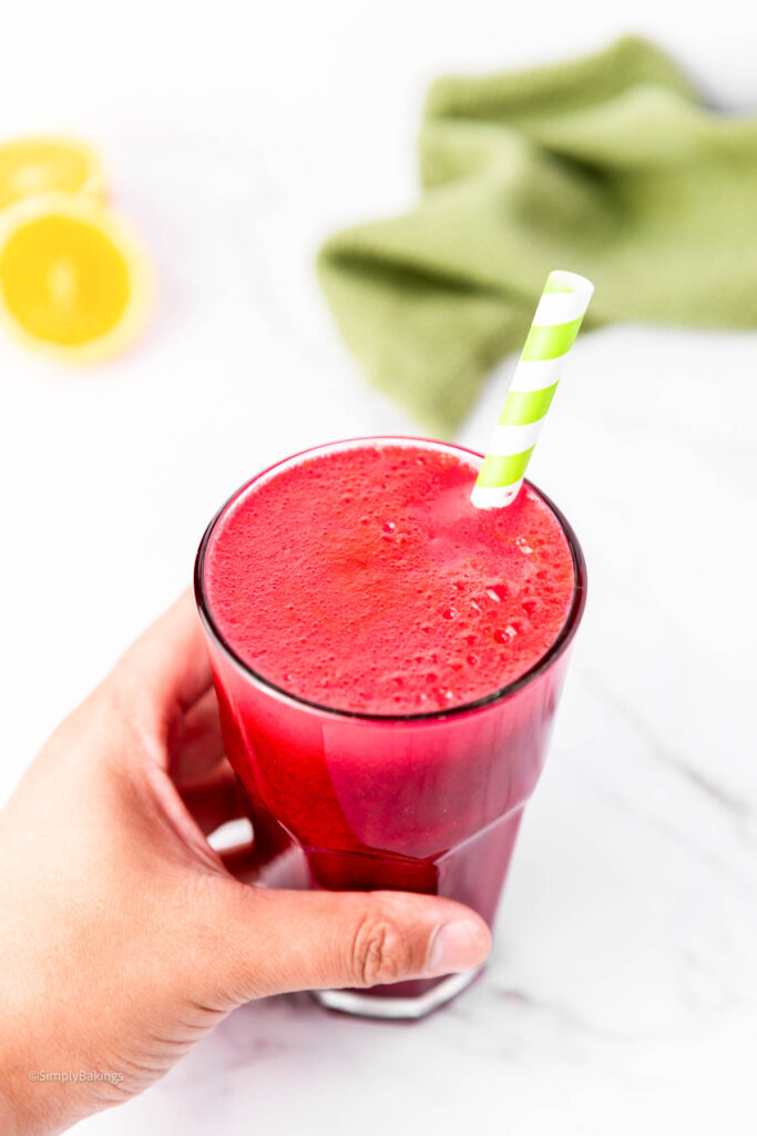 A hand holding a glass of the Red Juice recipe