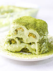 a slice of matcha tiramisu topped with matcha powder served on a white dessert plate