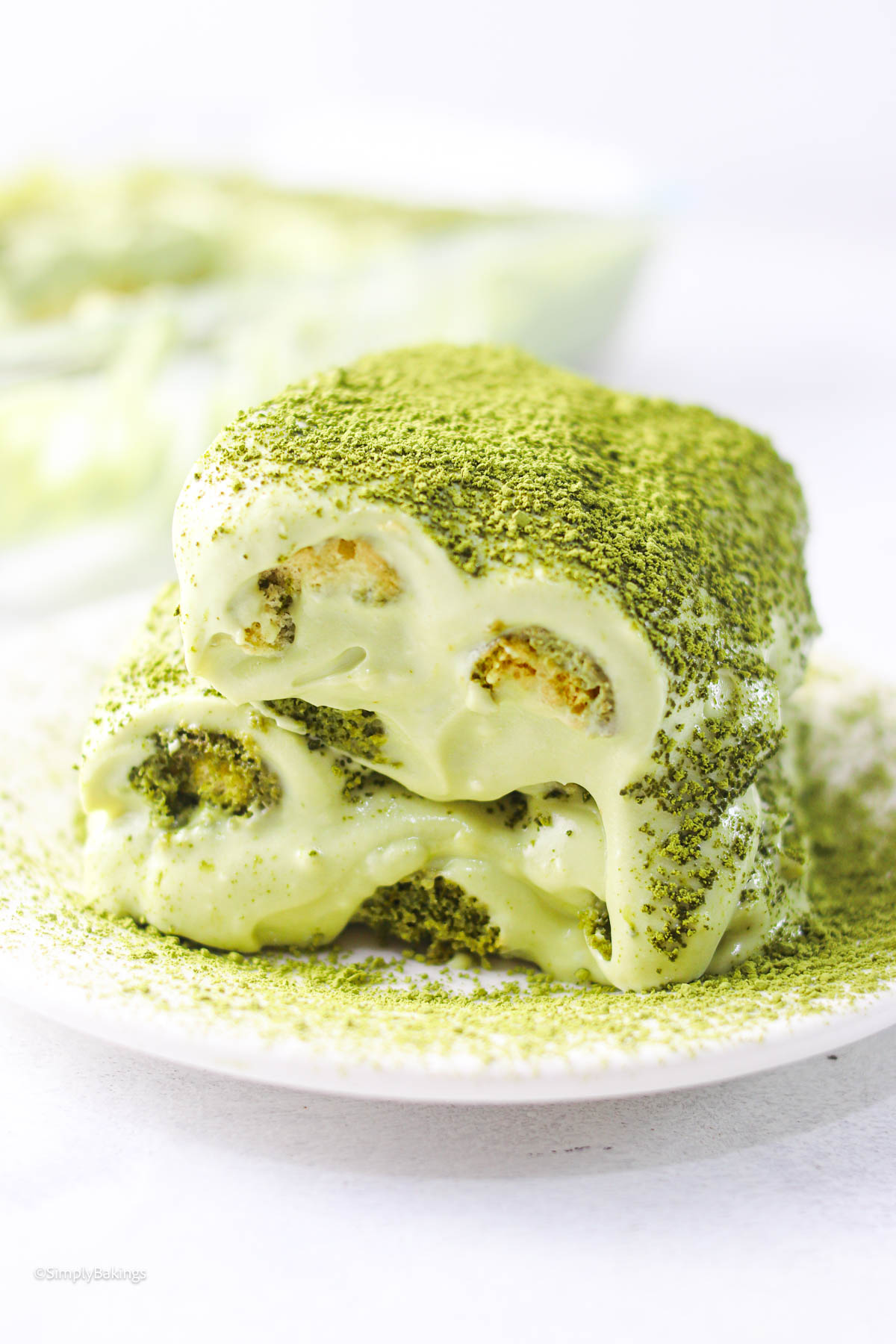 a slice of matcha tiramisu topped with matcha powder served on a white dessert plate