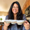 Lainey in the kitchen holding a cupcake pan with glasses