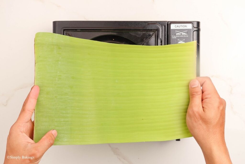 Putting banana leaves over a stove flame