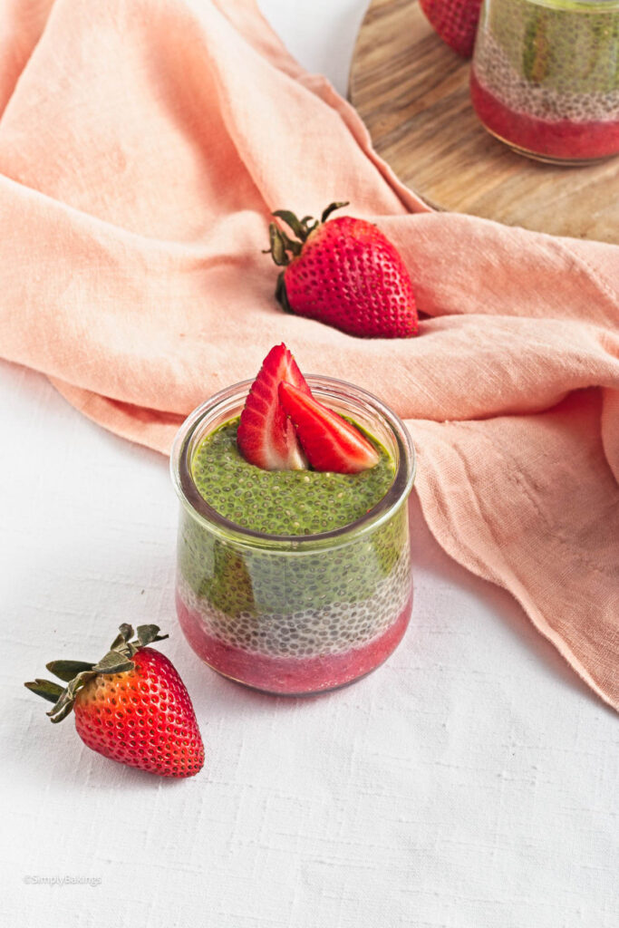a glass of Strawberry Matcha Pudding topped with sliced strawberries