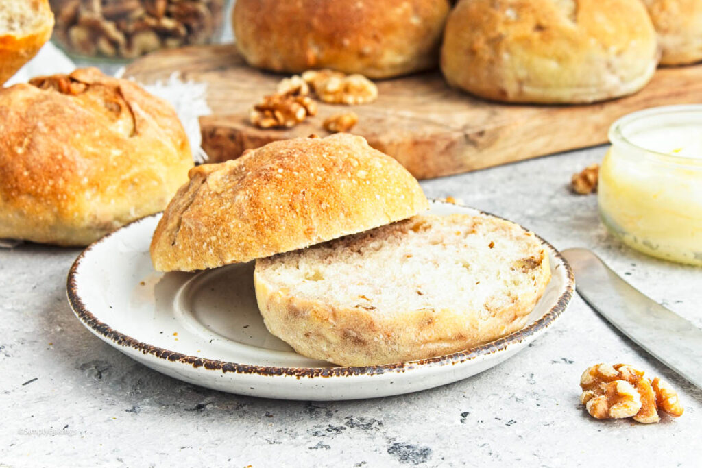 a crusty walnut roll sliced in halves and served in a small white plate