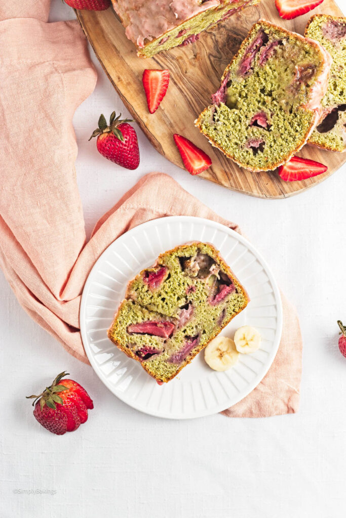 A slice of Strawberry Matcha Bread beside 2 banana slices on a small white plate