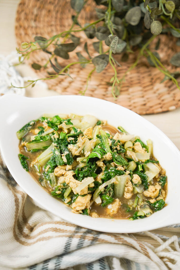 a serving of stir-fried pechay dish with scrambled eggs in a white bowl