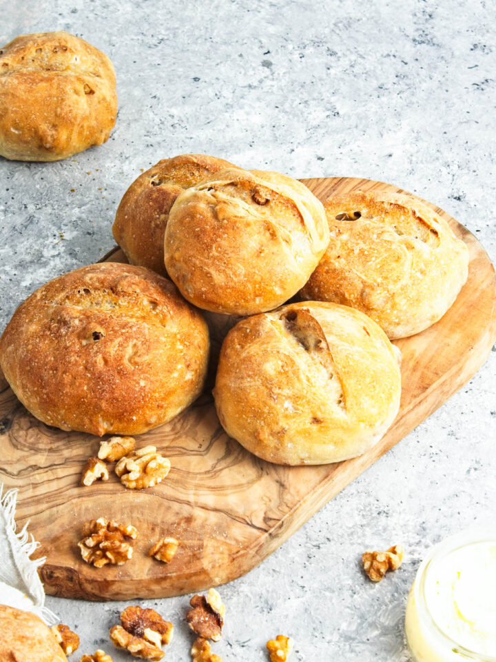 some crusty walnut rolls served on a wooden board