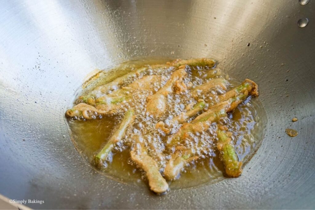 Frying string beans coated in batter in the pan