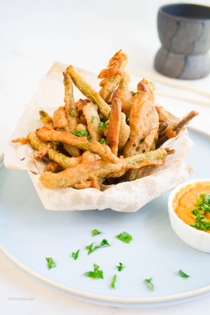 Deep-fried string beans in a bowl served on a sky-blue plate at the table