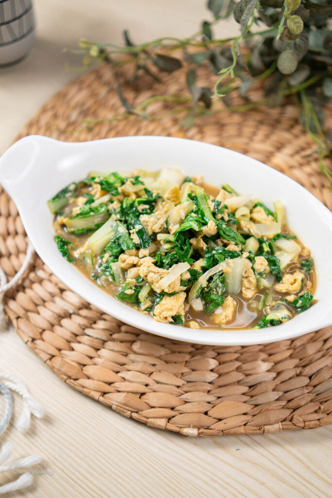 cooked stir-fried pechay and eggs served in a white bowl