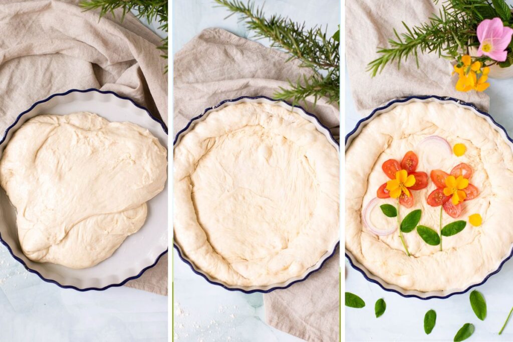 focaccia dough on a baking sheet topped with sliced tomatoes, onions, and fresh rosemary leaves, forming two flowers